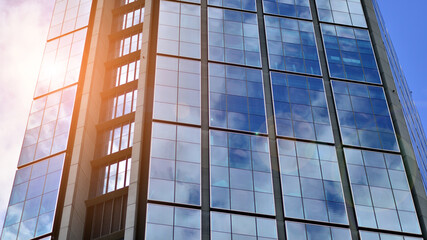  Modern glass facade against blue sky. Bottom view of a  building in the business district. Low angle view of the glass facade of an office building.