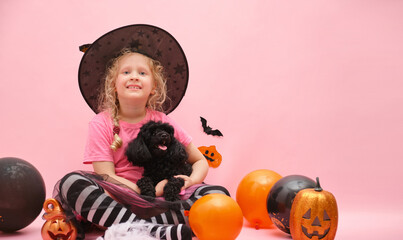 cheerful cute girl and little black mini poodle on the background of halloween scenery