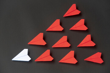 White paper plane origami leading red planes on dark background. Leadership skills concept