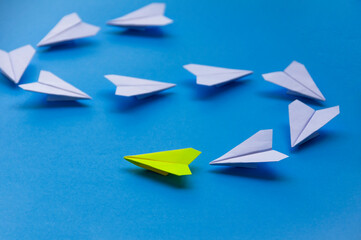 Yellow paper plane origami leading white planes on blue background. Leadership skills concept