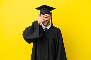 Young university graduate caucasian man isolated on yellow background covering eyes by hands and smiling