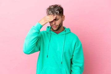 Young handsome caucasian man isolated on pink background with headache