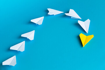 Yellow paper plane origami leading white planes on blue background. Leadership skills concept