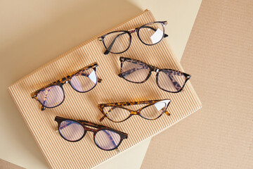 trendy fashion plastic eye glasses on box corrugated cardboard, beige background, optic store...