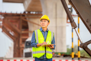 Engineer checking project at the building site, Man in hardhat with clipboard checklist at the infrastructure construction site