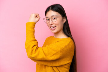 Young Chinese woman isolated on pink background With glasses and celebrating a victory