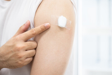 A man with medical plaster on arm after get covid 19 vaccine