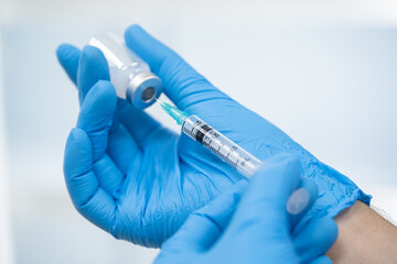 Doctor hand in blue gloves holding covid-19 vaccine preparing for vaccination shot, medicine and drug concept. (select focus)