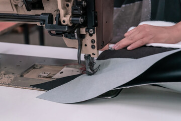 The seamstress sews on an old sewing machine, threads the fabric. Women's hands