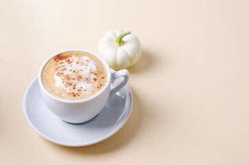 Coffee with foam and cinnamon in a white cup on a light background