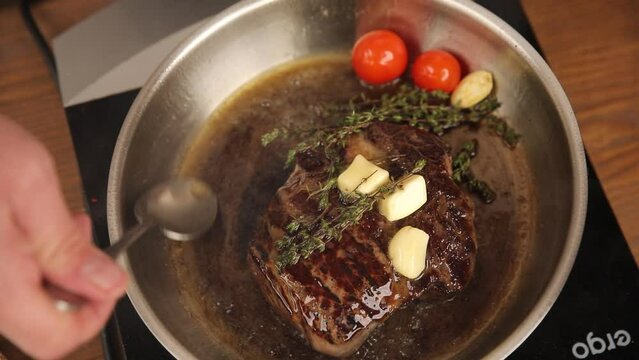the chef cooks a steak in a frying pan
