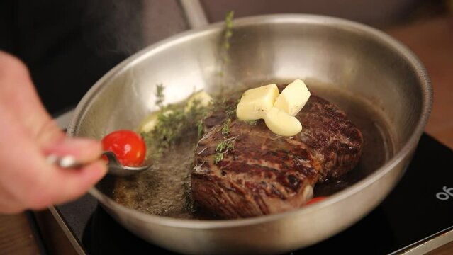 the chef cooks a steak in a frying pan
