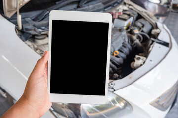 Technician Uses a empty tablet computer for check the operation of the car engine. Concept of car engine maintenance.