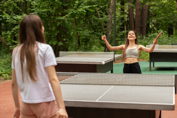 table tennis winner, happy girl with a racket raised her hands up, rejoices at the victory, sports...