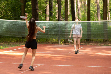 Fototapeta premium badminton tournament, teenager sport outdoor in the park in nature on a sunny summer day, two girls playing with badminton rackets in the park