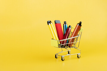 disposable vape in a trolley,electronic cigarettes in a shopping cart on a yellow background