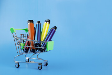 disposable vape in a trolley, electronic cigarettes in a shopping cart on a blue background