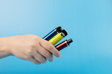 different electronic cigarettes in the smoker's hand on a blue background