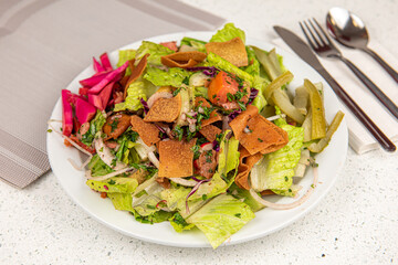 Healthy fattoush salad closeup. The key ingredient in this middle eastern dish is the toasted pita bread which is mixed with healthy vegetables, herbs and a dressing made with lemon and sumac.