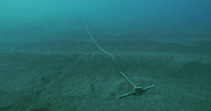 Small boat anchor embedded in seabed short scope pan up.