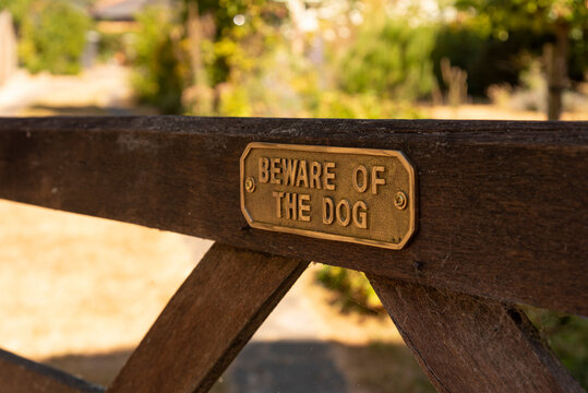 Hampshire, England, UK. 2022. Beware of the dog brass sign on a wooden five bar gate.
