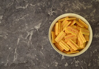 Bacon crisps in a bowl on dark background.