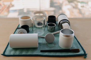 Set of portable french press and grinder coffee equipments on green cloth.