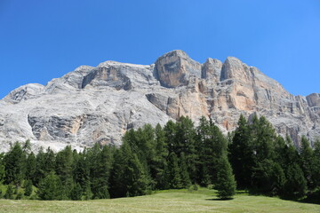 Val Badia, Italy-July 17, 2022: The italian Dolomites behind the small village of Corvara in summer days with beaitiful blue sky in the background. Green nature in the middle of the rocks.