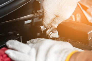 Close-up hand mechanic with his tool holding a spanner while for change battery in the car at a...