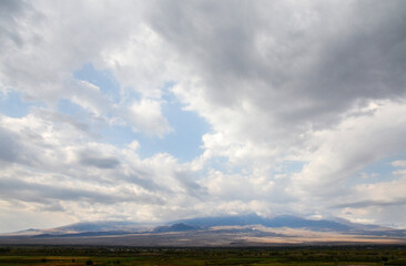 Landscape of valley with Ararat mountain behind the low clouds from Armenian side