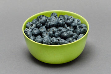 Fresh blueberries in a bamboo plate on a dark background