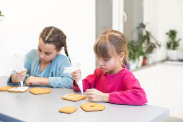 two little girls making gingerbread cookies at home.