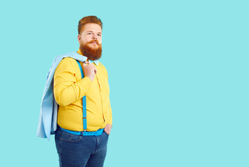 Redhead Caucasian man with beard and mustache posing next to copy space throwing jacket over back...