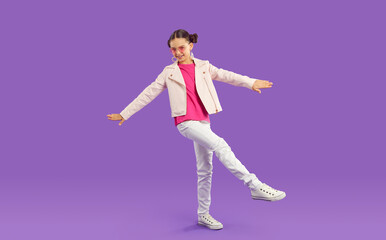 Fototapeta na wymiar Happy kid in trendy outfit. Girl in pale pink leather jacket, pink tee, white pants and sneakers standing on purple studio background. Full body length shot. Children's fashion, casual clothes concept