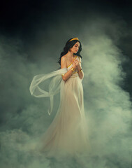 Fantasy Greek goddess woman fashion model walks in dark sky clouds. Girl Aphrodite sexy queen old...
