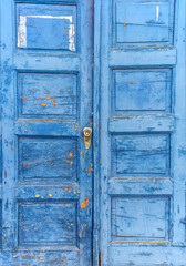 Old antique blue wooden door with paint that is peeling off.