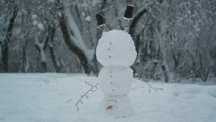 Happy funny snowman acrobat standing on his head, on background of a strong snowfall. Snowman...