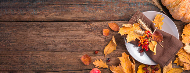 Plates, cutlery and autumn leaves on a wooden background. Festive, autumn background. The concept of Halloween, Thanksgiving. Top view