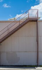 Brown Metal Building Stairs to a Roof and Blue Sky.