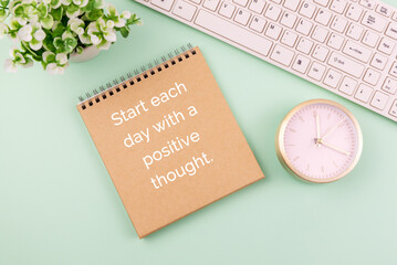 Brown paper with computer keyboard and alarm clock and  text - start each day with a positive thought on paper note