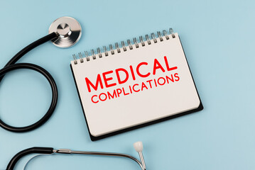 Medical complications text on note pad and stethoscope - obrazy, fototapety, plakaty