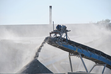 Industrial conveyor belt transports building material, small crushed stone.