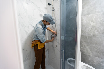 repairmen in uniform measuring modern shower cabin in bathroom.