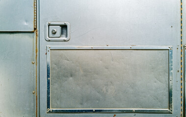 Compartment door on the side of a silver metallic horse trailer