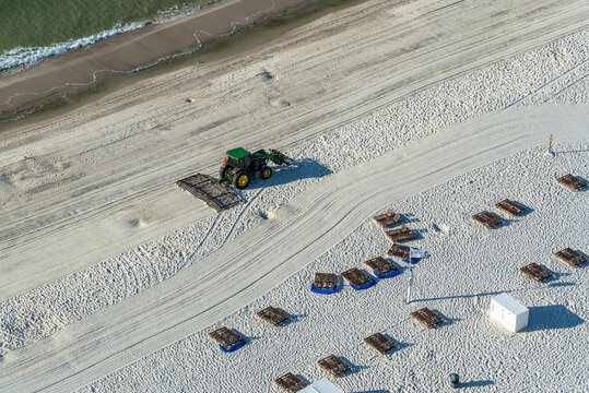 Tractor grooming white sand beach.