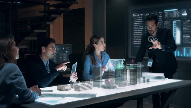 Businessman in Suit presenting 5G Wireless Network Connection to Colleagues and Partners sitting around Futuristic Table with Holographic Modern Augmented Reality Technology. 3D Model of City.