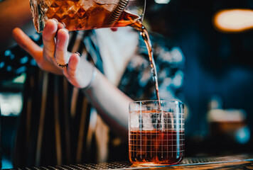 woman hand bartender making negroni cocktail in bar