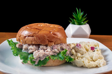 tuna fish  between a brioche bun with potato salad,