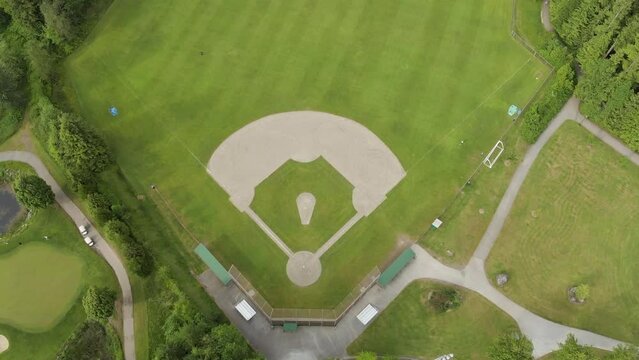 A top down aerial drone view of a green baseball field, baseball diamond, sports field, community park. 4K 24FPS.