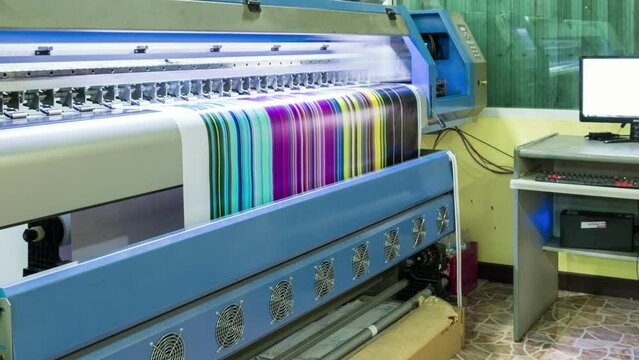 Technician printing vinyl multi color cmyk on large inkjet printer in workplace